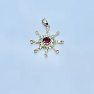 Macro shot of sunburst gold pendant featuring a ruby center and orange gemstones