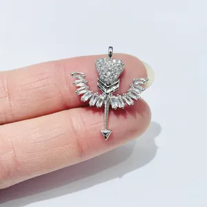 Sparkling silver winged heart arrow pendant with baguette zircons held on fingertips