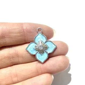 Silberner vierblättriger Blumenanhänger mit hellblauem Emaille und Zirkonia in der Hand