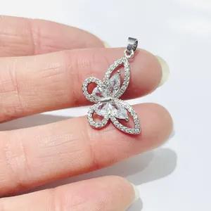 Detailed view of a silver butterfly pendant with crystals held to show size scale