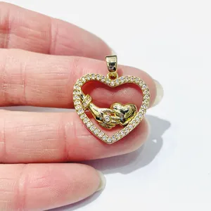 Detailed view of a gold heart pendant featuring a handshake design and inlaid crystals