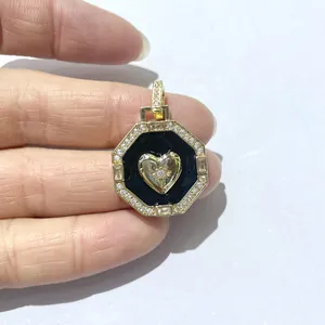 Macro shot of gold octagonal pendant with black enamel heart and cubic zirconia stones