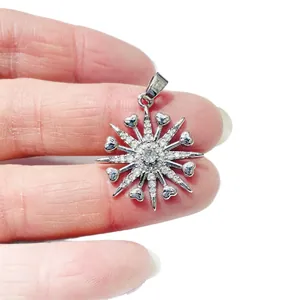Silver snowflake pendant with zircons and tiny hearts held against white background
