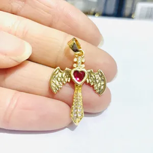 Makro-Detail von Kreuzanhänger mit rotem Herz-Edelstein und Zirkonia-Flügeln in Gold