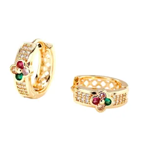 Elegant gold huggie earrings with four-leaf flower and colorful zircon stones on white background