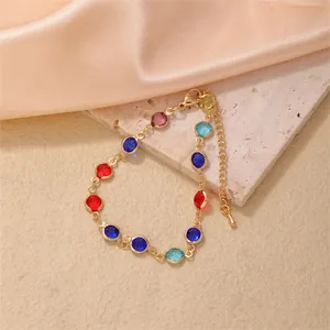 Golden bracelet with colorful round glass stones on stone and peach satin background