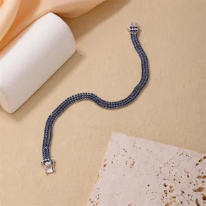 Detailed close-up of triple-row blue gemstone tennis bracelet with silver claw settings