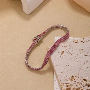Detailed macro view of triple-row tennis bracelet with red crystals and silver buckle