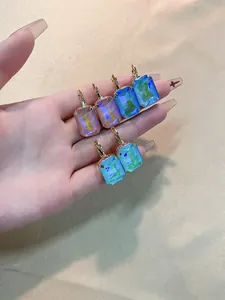 Hand holding three pairs of square colorful zircon earrings with gold leverback closure