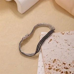 Detailed macro view of triple-row tennis bracelet with black cubic zirconia and secure clasp