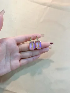 Detail of rectangular iridescent crystal earrings with gold hooks on silk backdrop