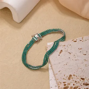 Macro shot of three-row tennis bracelet with green crystals and secure silver clasp