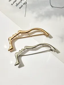 Spille dal profilo astratto artistico in finitura oro e argento su una rivista