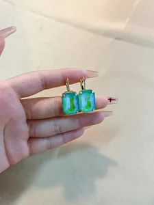 Macro view of emerald-cut green crystal earrings with leverback gold settings