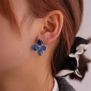Nahaufnahme der blauen Edelstein-Ohrringe mit gedrehtem Metallrand am Model getragen