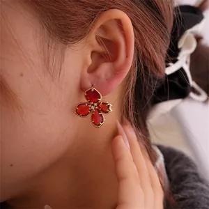 Nahaufnahme luxuriöser roter Blumenohrringe mit Goldperlenrand und Zirkon-Detail