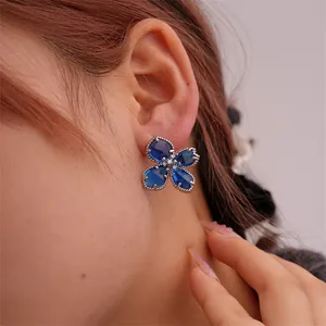 Nahaufnahme der tiefblauen Blumenohrringe mit Vintage-Silberperlenrand am Ohr