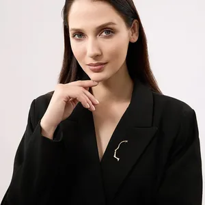 Spilla minimalista dorata con profilo astratto del viso su risvolto nero donna