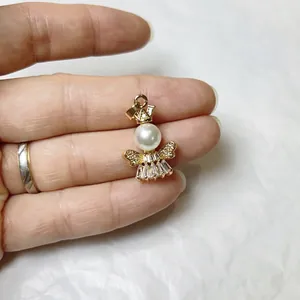 Macro shot of an angel pendant with gold alloy frame, white pearl head and zircon wings