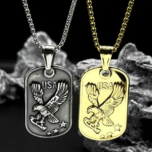 Close-up of gold and silver eagle dog tag pendants on a box chain over a rock surface