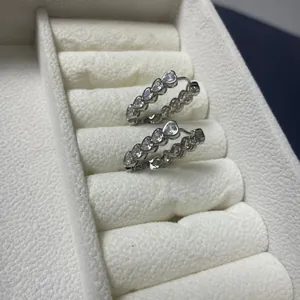 Detail view of heart-shaped zircon pavé earrings on a white velvet jewelry box