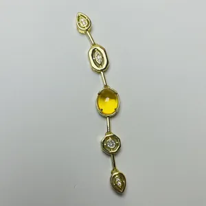 Detail of a vintage golden necklace featuring a central yellow citrine and geometric zirconia