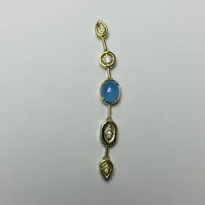 Close-up of a gold tassel pendant featuring a blue oval stone and sparkling zircon accents