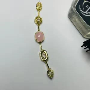 Detail of gold chain necklace featuring a pink oval gemstone and sparkling zircon accents