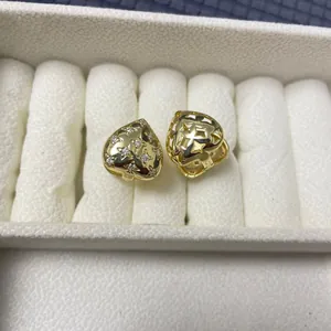 Detail of heart-shaped gold earrings with white zircons and hollow star pattern