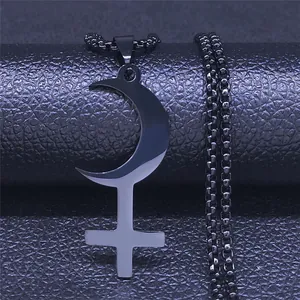 Macro shot of gothic black moon crescent and cross pendant on stainless steel ball chain