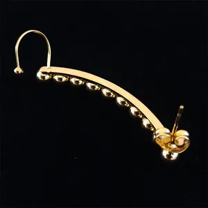 Macro detail of golden curved ear cuff featuring metallic beads and butterfly backing