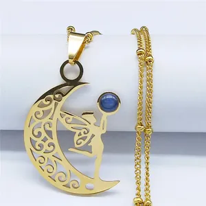 Macro detail of golden crescent moon pendant with intricate hollow fairy and blue bead