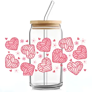 Close-up of clear 16oz glass can with pink concha heart pattern, bamboo lid and glass straw