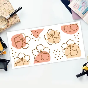 Detail eines UV DTF Blumenaufklebers auf weißem Tisch mit Reisezubehör
