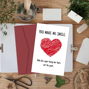 Flat lay of funny heart greeting card with red envelope on a natural wood desk