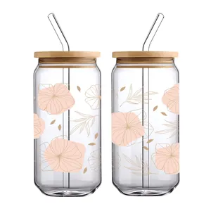 Detail von zwei 16oz Gläsern mit Bambusdeckeln, Glasstrohhalmen und floralen UV DTF Stickern
