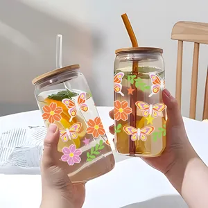 Dettaglio di tazze in vetro da 16oz con adesivi UV a fiori e farfalle colorate