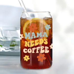 Detail van de UV-DTF transfersticker op een 16oz glas met Mama Needs Coffee design