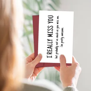 Funny miss you birthday card with envelope held in hands in a warm indoor setting
