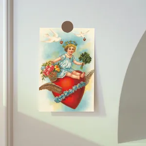 Close-up of vintage Cupid postcard with child on heart pinned to a wall by magnet