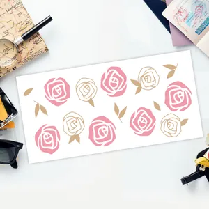 Flat-lay Detail von UV DTF Rosensticker auf 16oz Glas mit Reisedekoration Zubehör