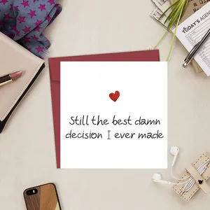 Flat lay of heart greeting card and red envelope with Still the best damn decision text