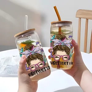 Verres en forme de canette avec stickers de coiffeur, couvercles bambou et pailles sur table