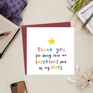 Flat lay of square card with colorful text and red envelope on a tidy desk setup