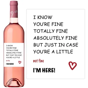 Close-up of pink wine bottle with white labels featuring red heart and quotes