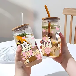 Gros plan d'un verre 16oz avec motifs de cœurs, couvercle en bois et paille en main