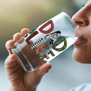 Detail van een hand die een 16oz glas vasthoudt met een kleurrijke DAD LIFE UV DTF-print