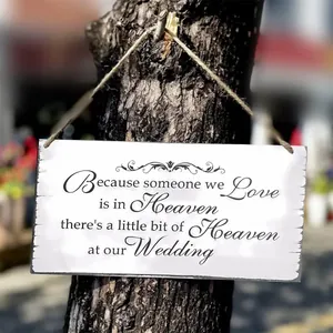 Close-up of white rustic wooden wedding memorial sign with black text and jute rope