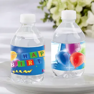 Close-up of birthday water bottle labels with colorful balloons and letter flag patterns