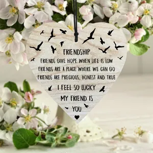 Close-up of heart-shaped wooden plaque with friendship poem and black bird silhouette